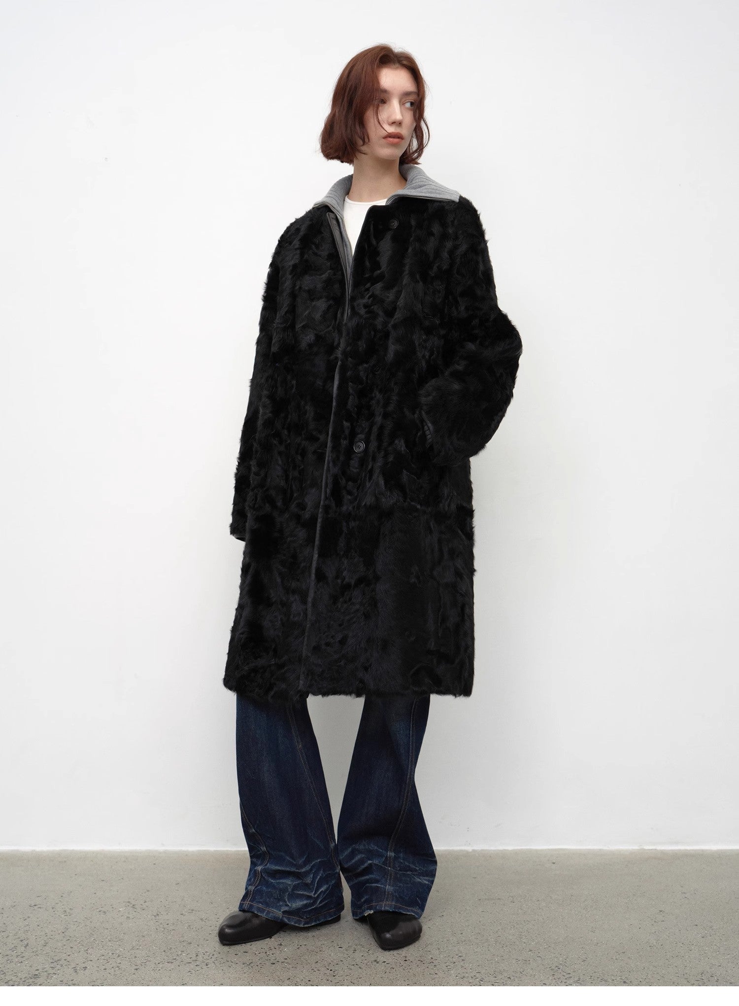 Person wearing a black textured coat against a white background