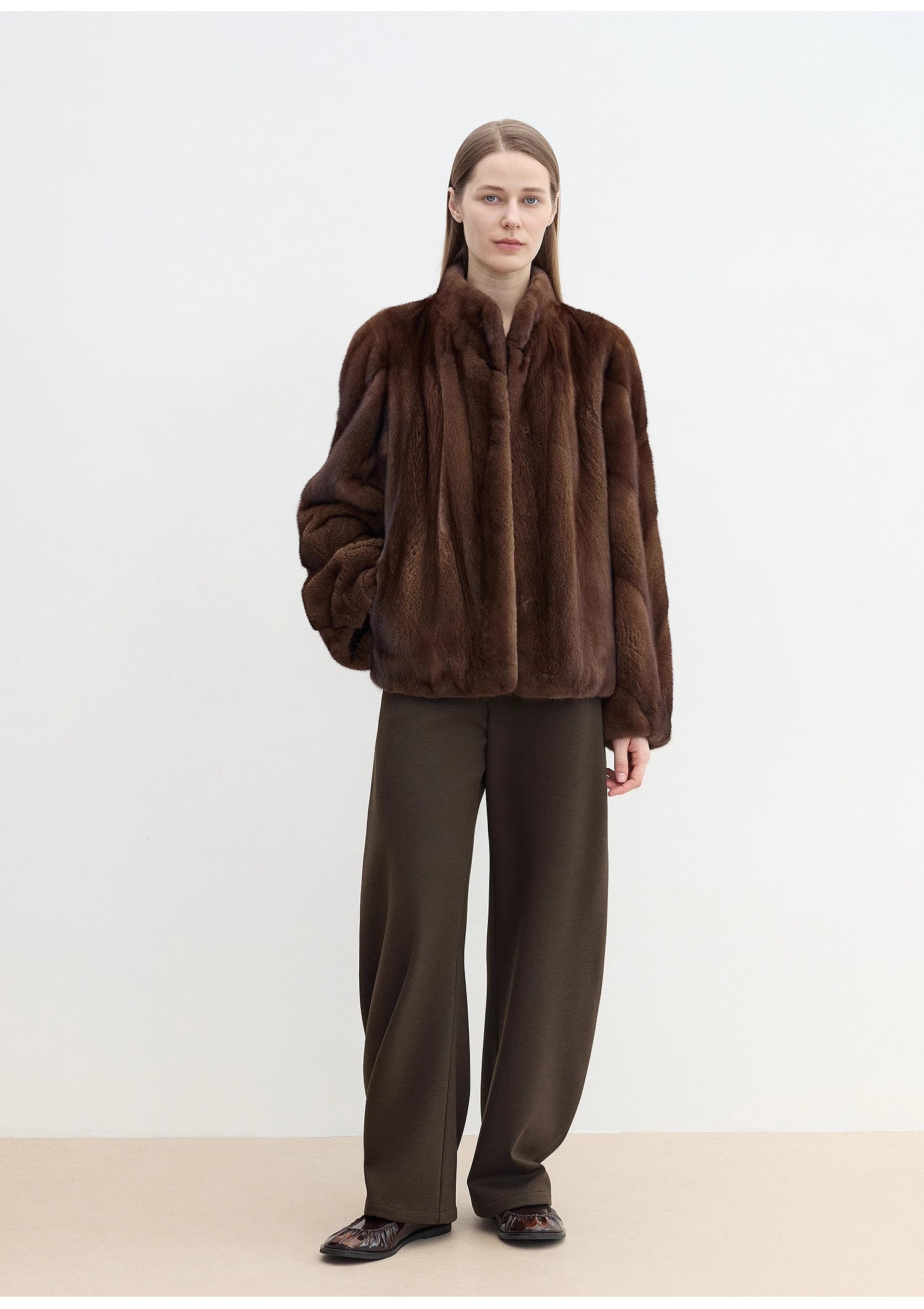 Person wearing a brown fur coat and pants on a white background