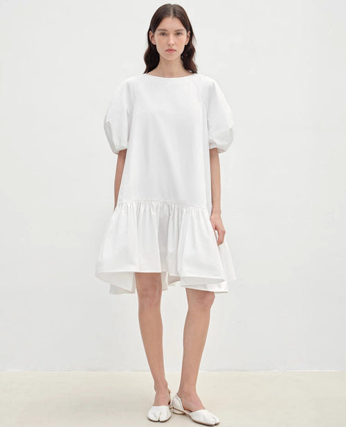 Woman wearing a white dress against a plain background