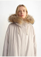 Person wearing a beige parka with a fur-lined hood on a white background