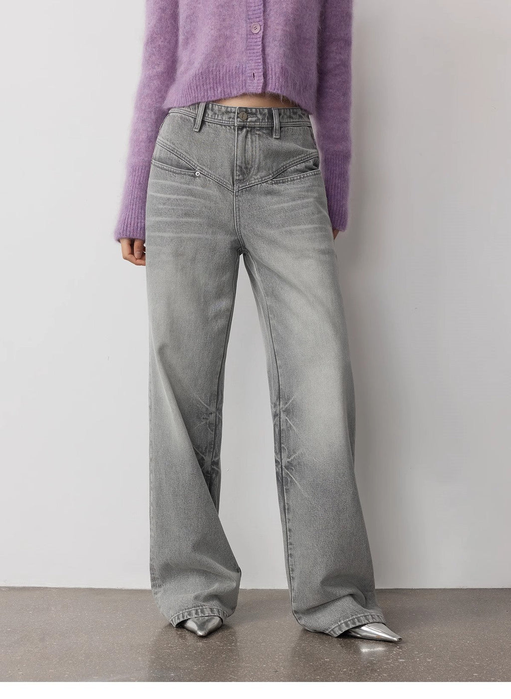 Person wearing gray wide-leg jeans and a purple cardigan against a plain background