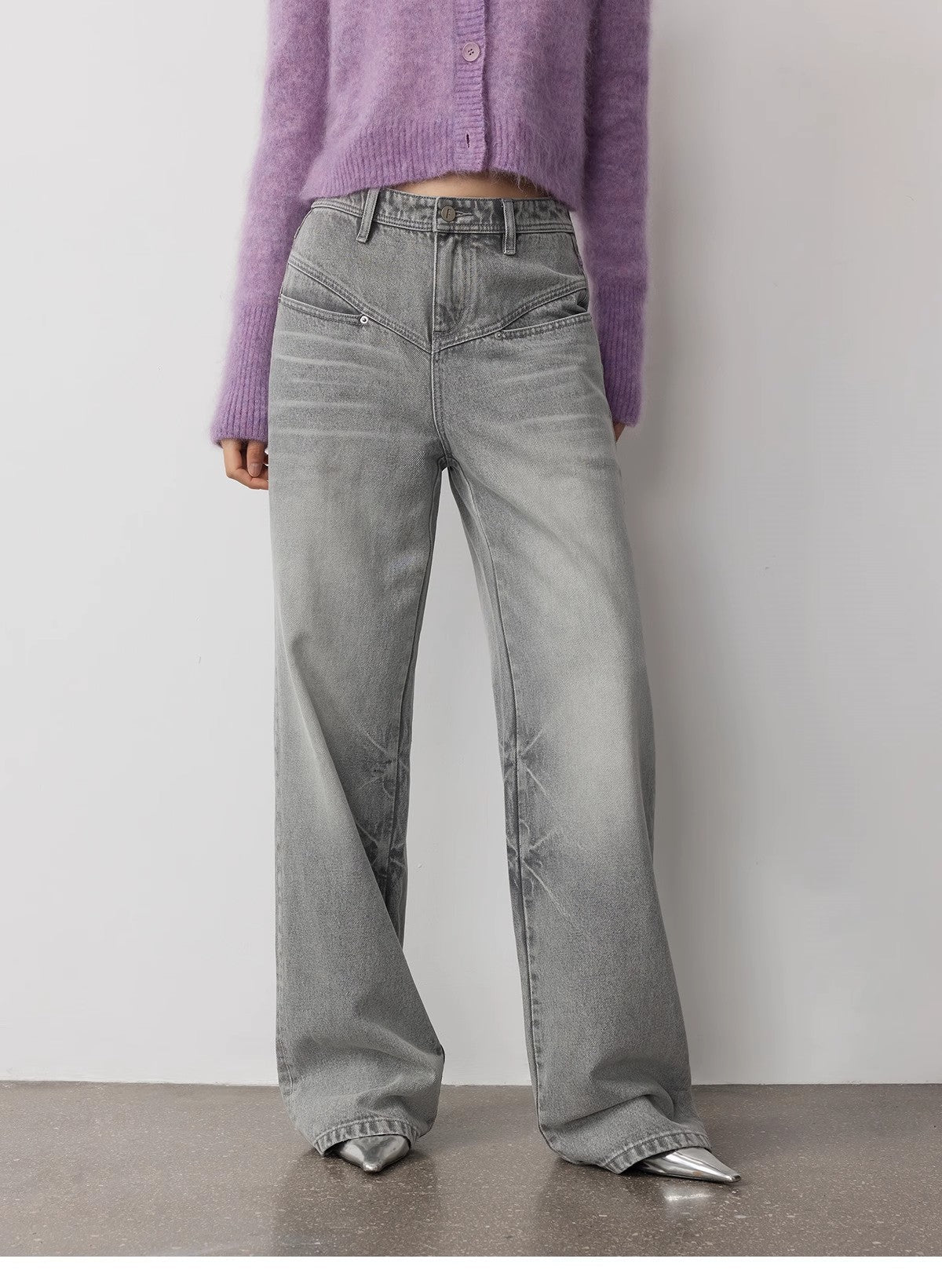 Person wearing gray wide-leg jeans and a purple cardigan against a plain background