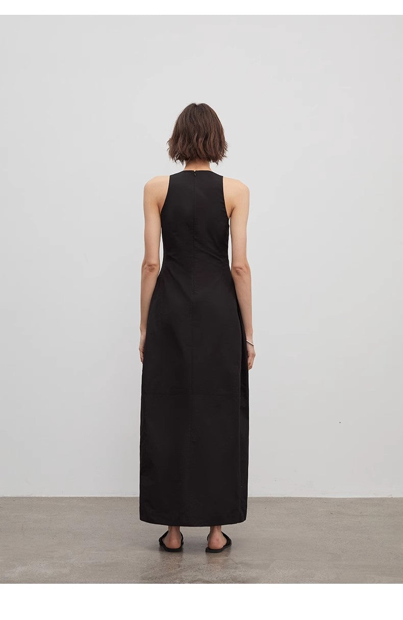 Person wearing a black sleeveless dress standing against a plain white background