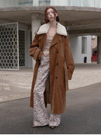 Person wearing a brown coat with white fur lining, beige top, and zebra print pants standing on a street.