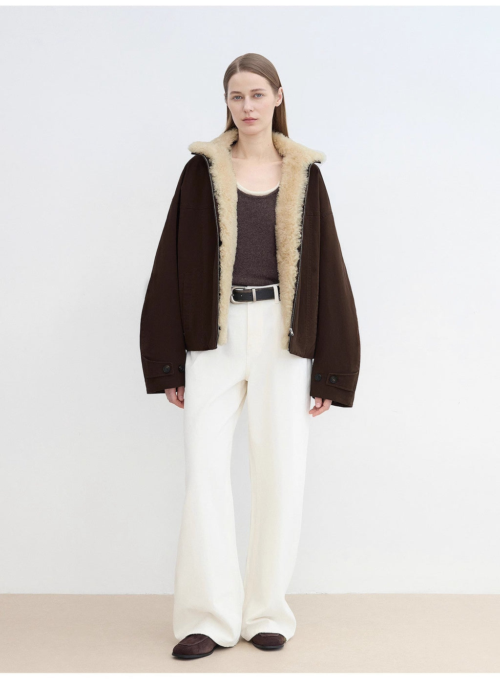 Woman wearing a dark brown coat with beige fur lining on a white background