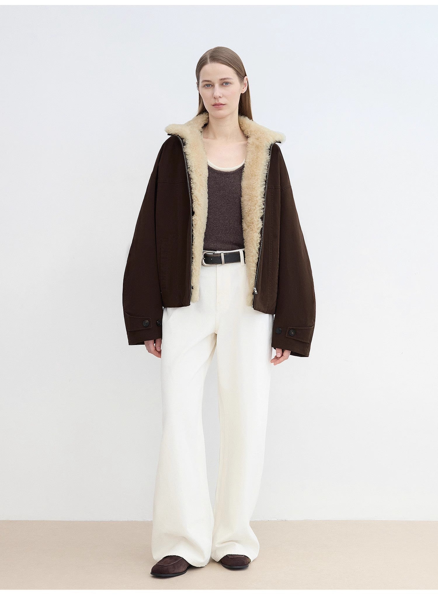 Woman wearing a dark brown coat with beige fur lining on a white background