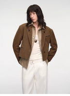 Person wearing a brown jacket over a white shirt and pants on a white background