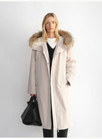 Woman wearing a long beige coat with a fur-lined hood against a white background
