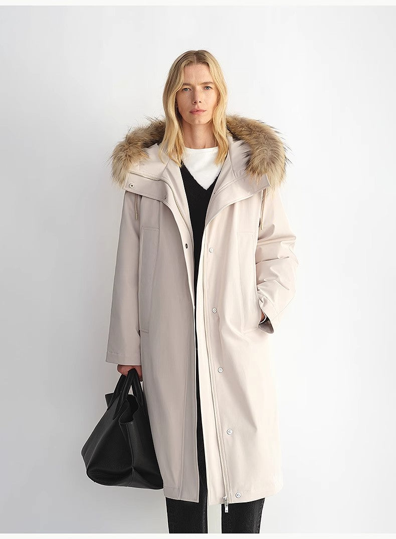 Woman wearing a long beige coat with a fur-lined hood against a white background