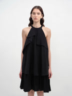 Woman wearing a black halter neck dress with layered design on a white background
