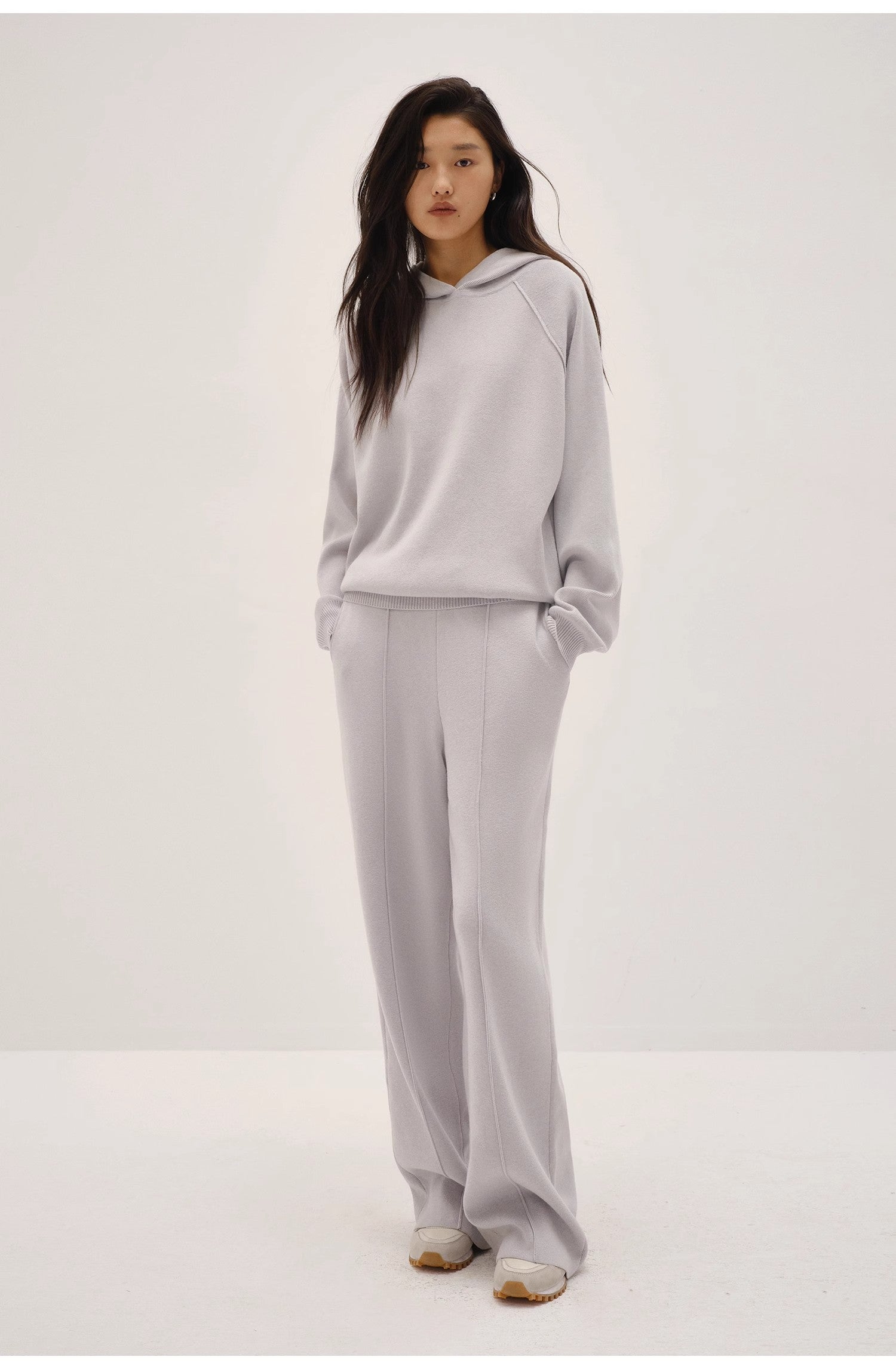 Person wearing a light gray hoodie and pants on a white background