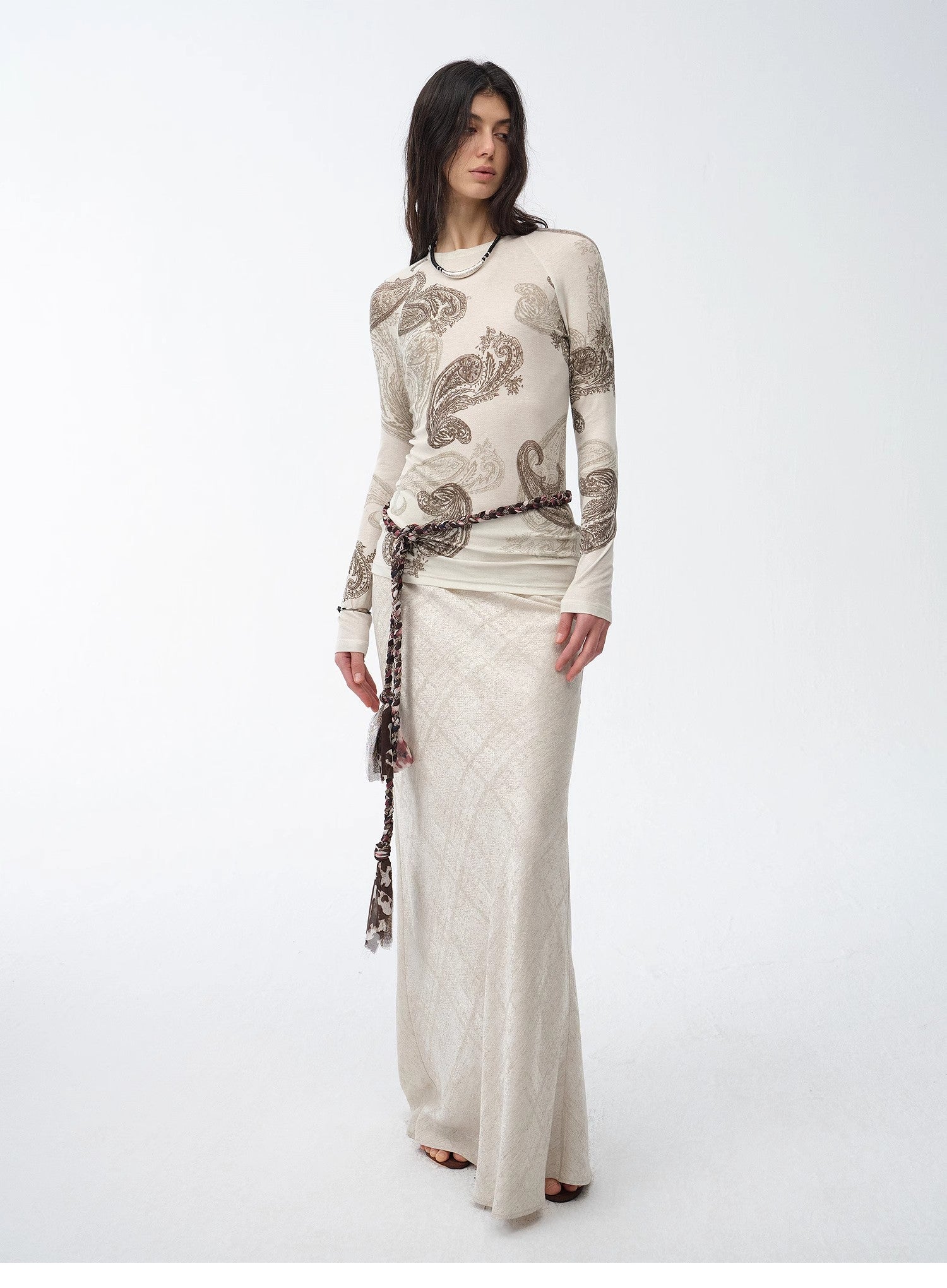 Woman wearing a long, patterned dress with a white background
