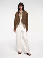 Person wearing a brown blazer and white pants on a white background