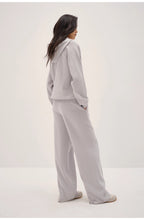 Person wearing a light gray hoodie and pants set on a white background