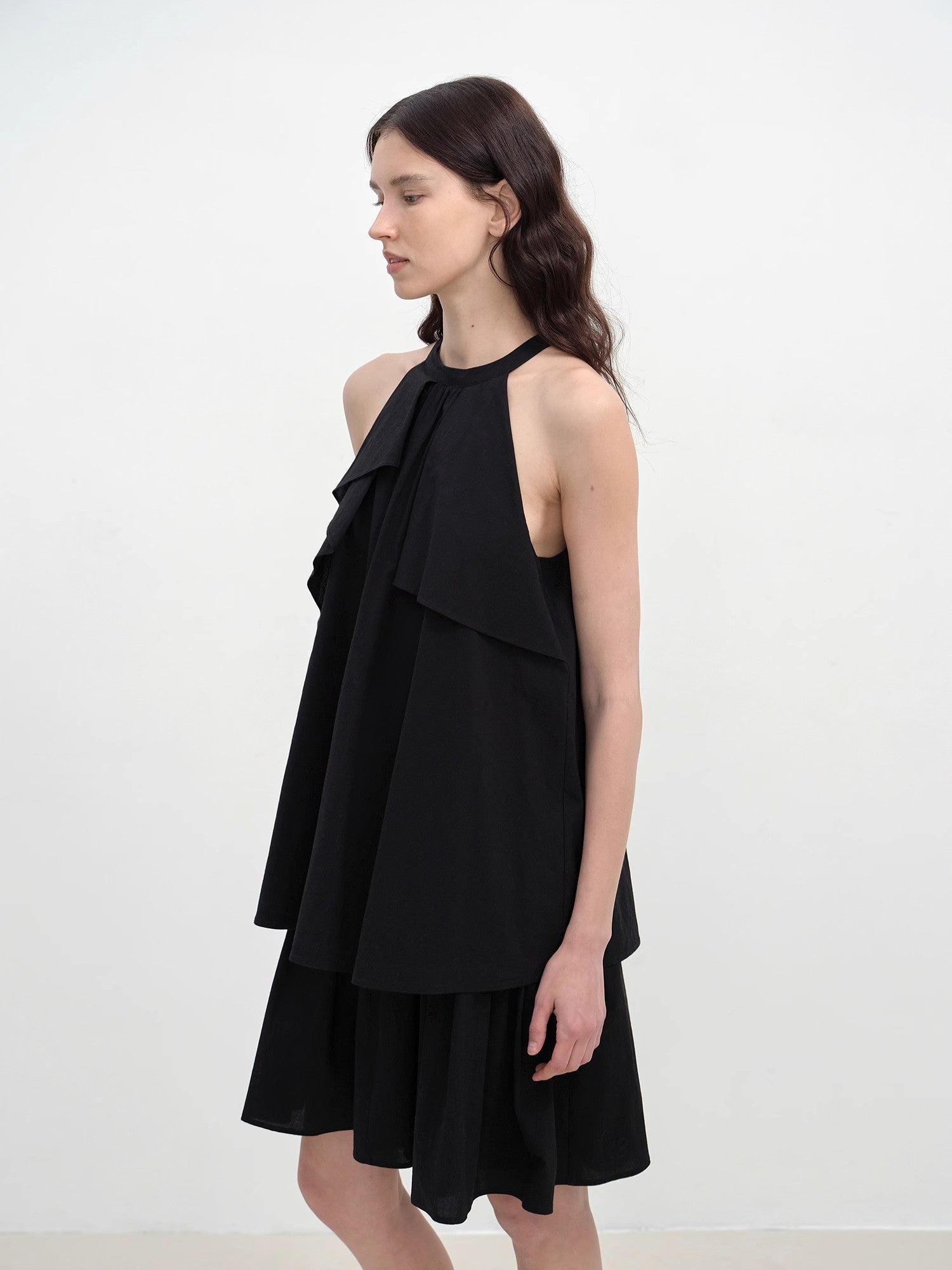 Woman wearing a black dress with ruffled layers on a white background