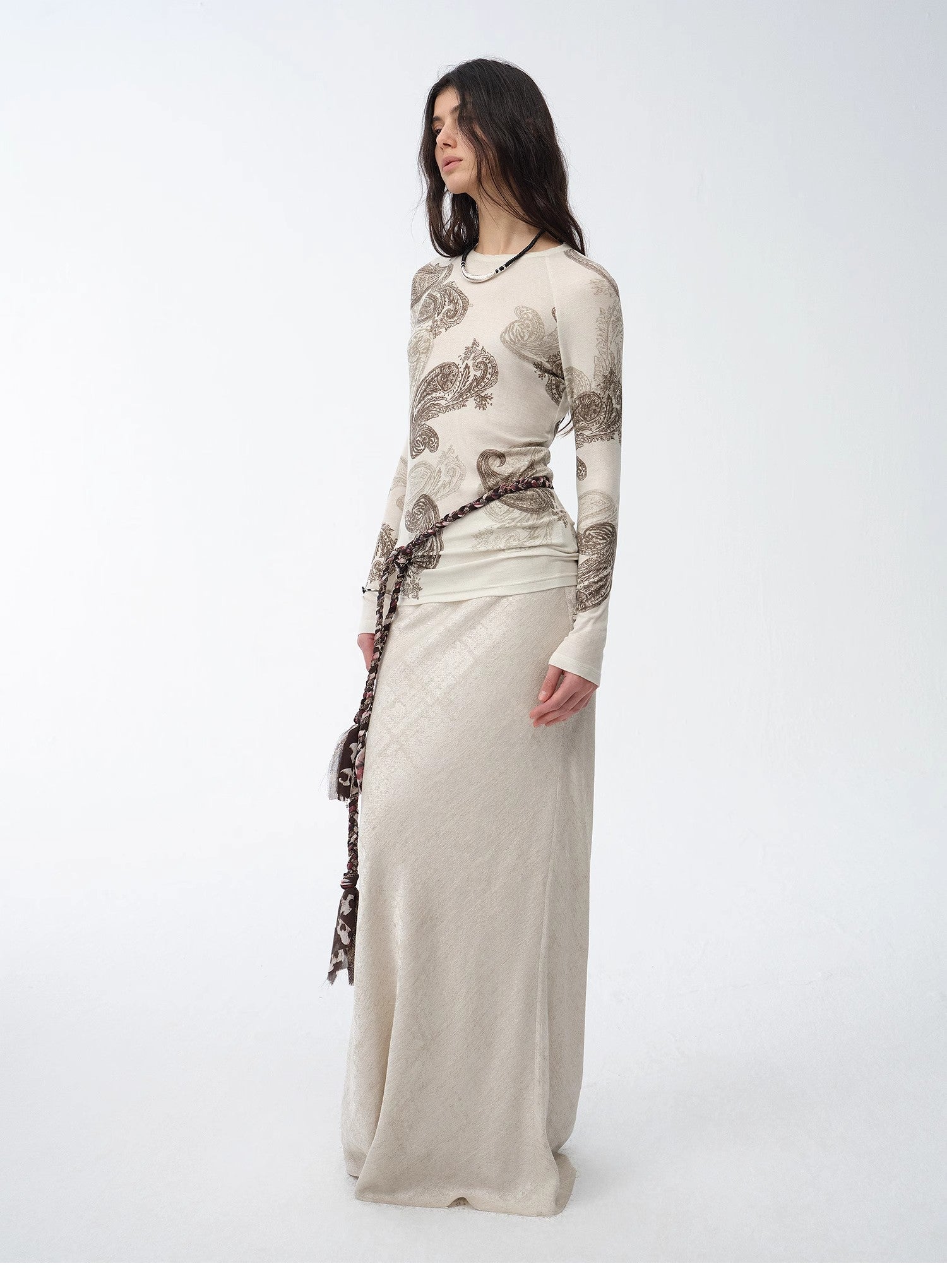 Woman wearing a long, elegant dress with intricate patterns on a white background