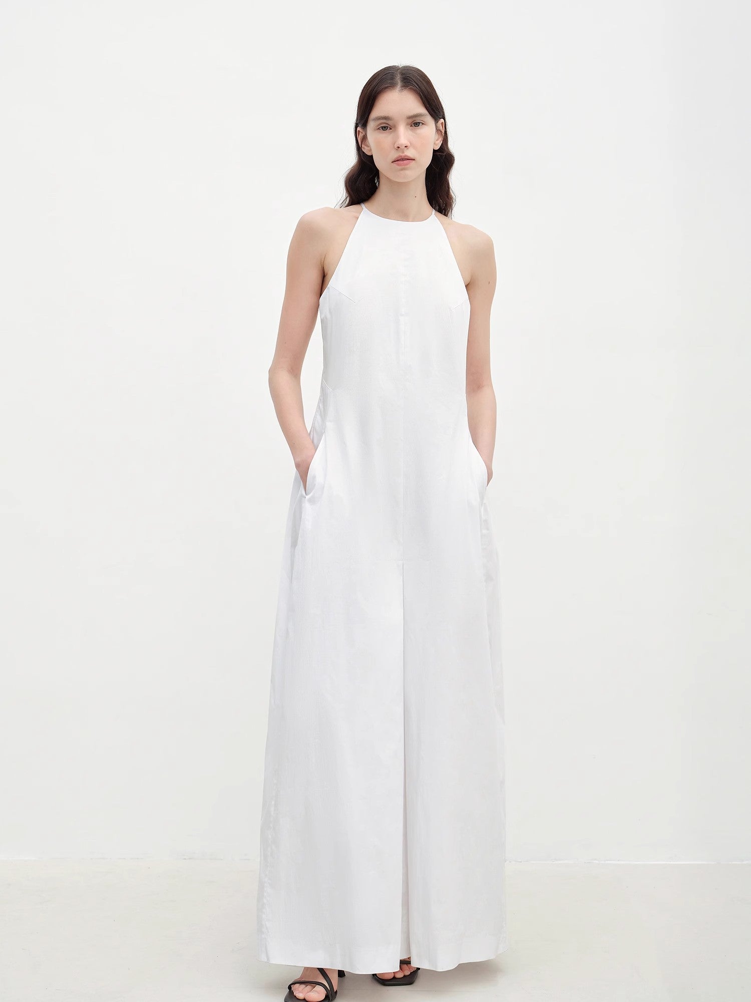 Woman wearing a white halter neck dress on a white background