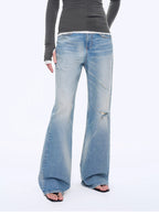 Person wearing blue flared jeans and a gray top on a white background
