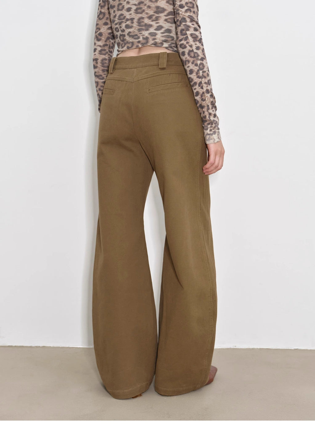 Person wearing brown wide-leg pants with a white background