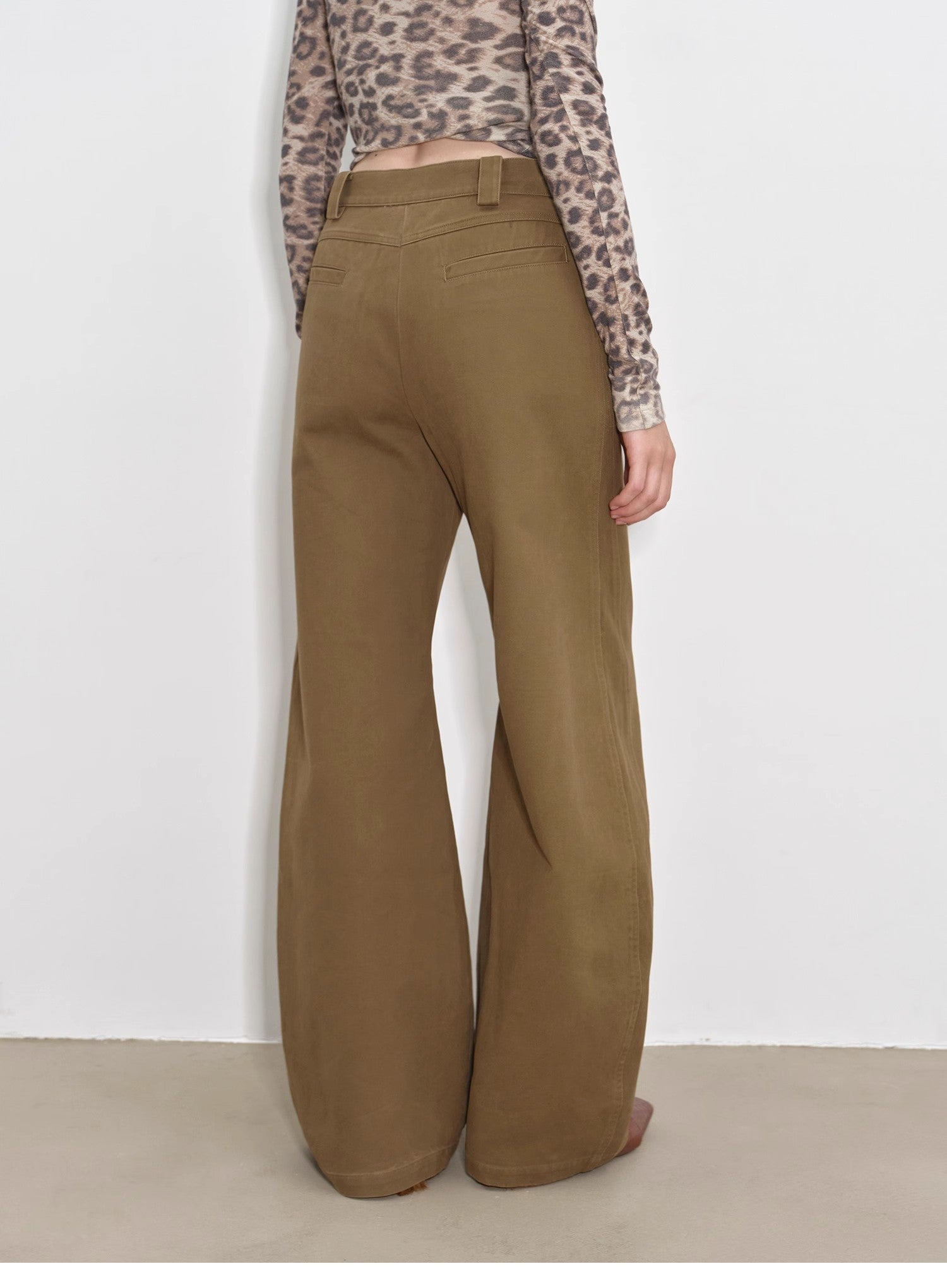 Person wearing brown wide-leg pants with a white background