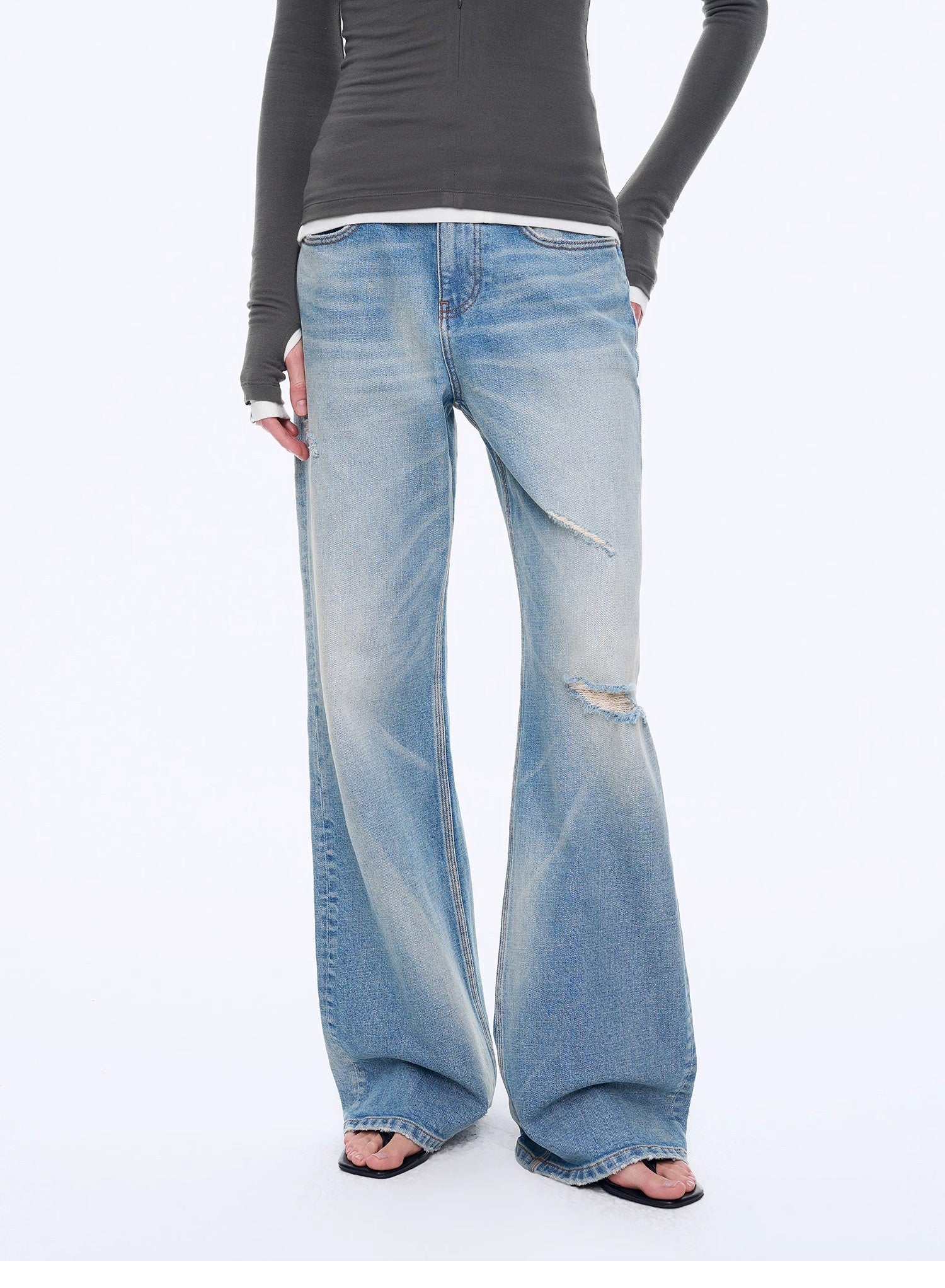Person wearing light blue flared jeans on a white background