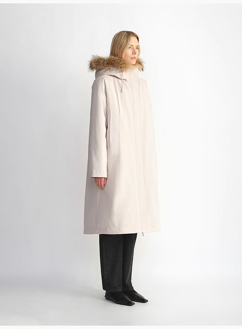 Woman wearing a long beige coat with fur hood on a white background