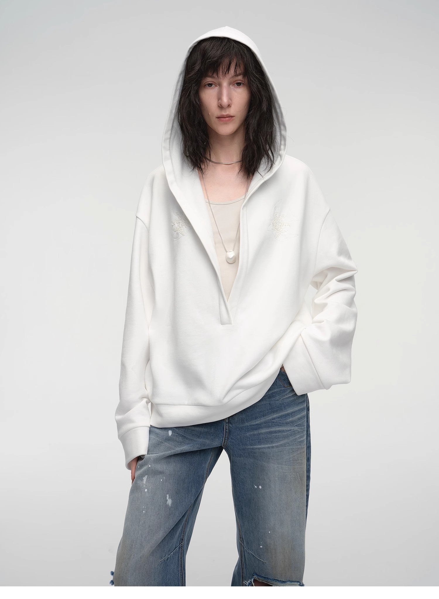 Person wearing a white hoodie and blue jeans on a plain background