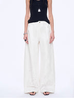 Person wearing a black top and white wide-leg pants on a white background