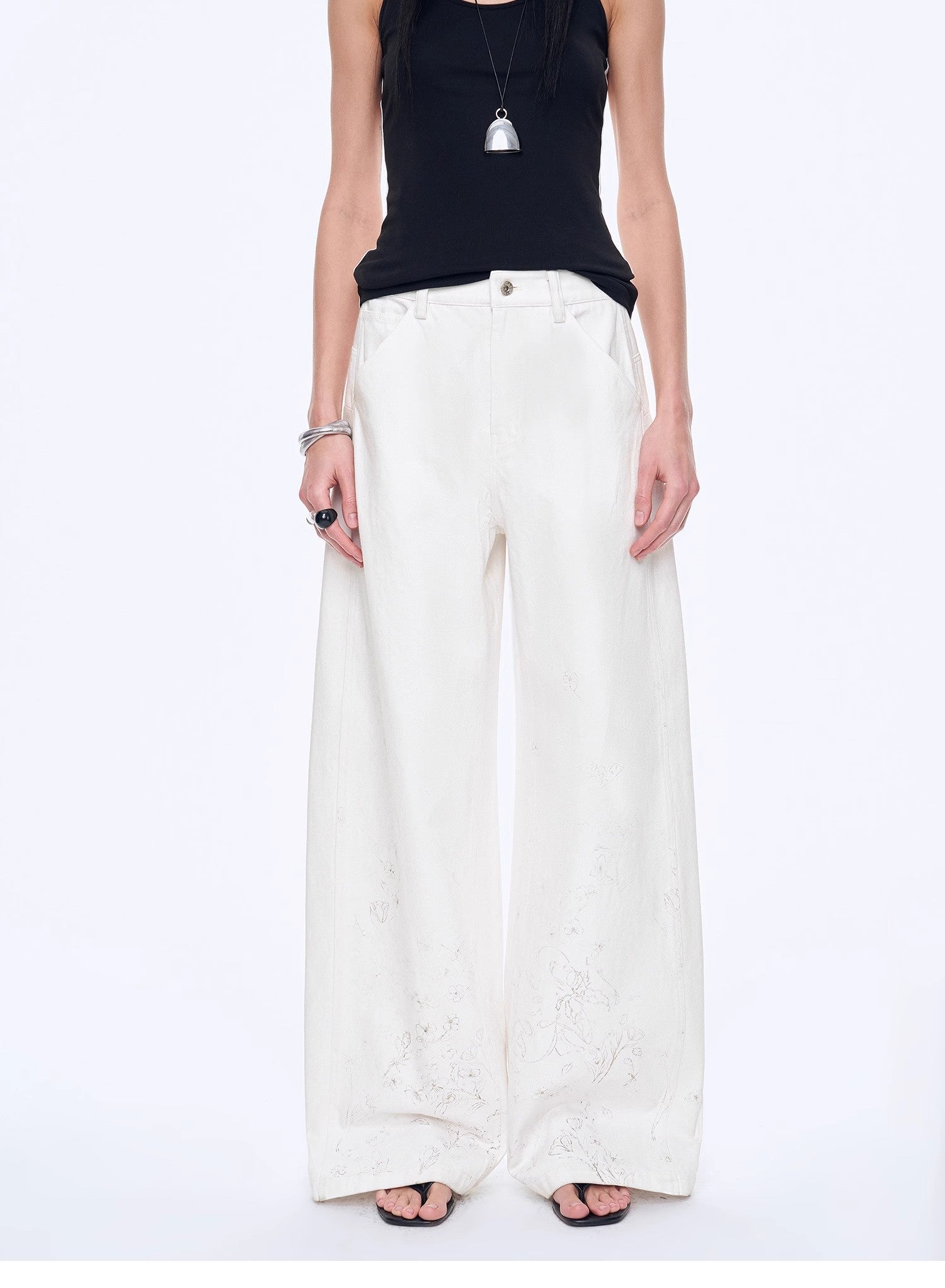 Person wearing a black top and white wide-leg pants on a white background