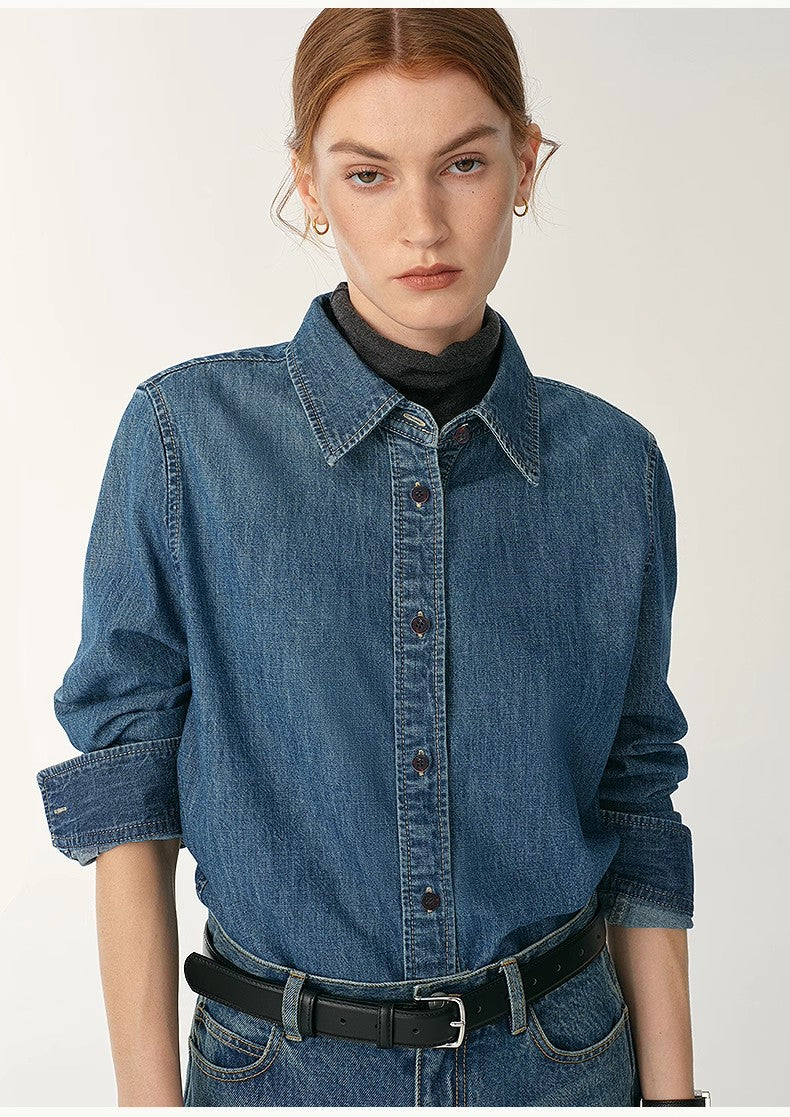 Woman wearing a blue denim shirt with a plain background