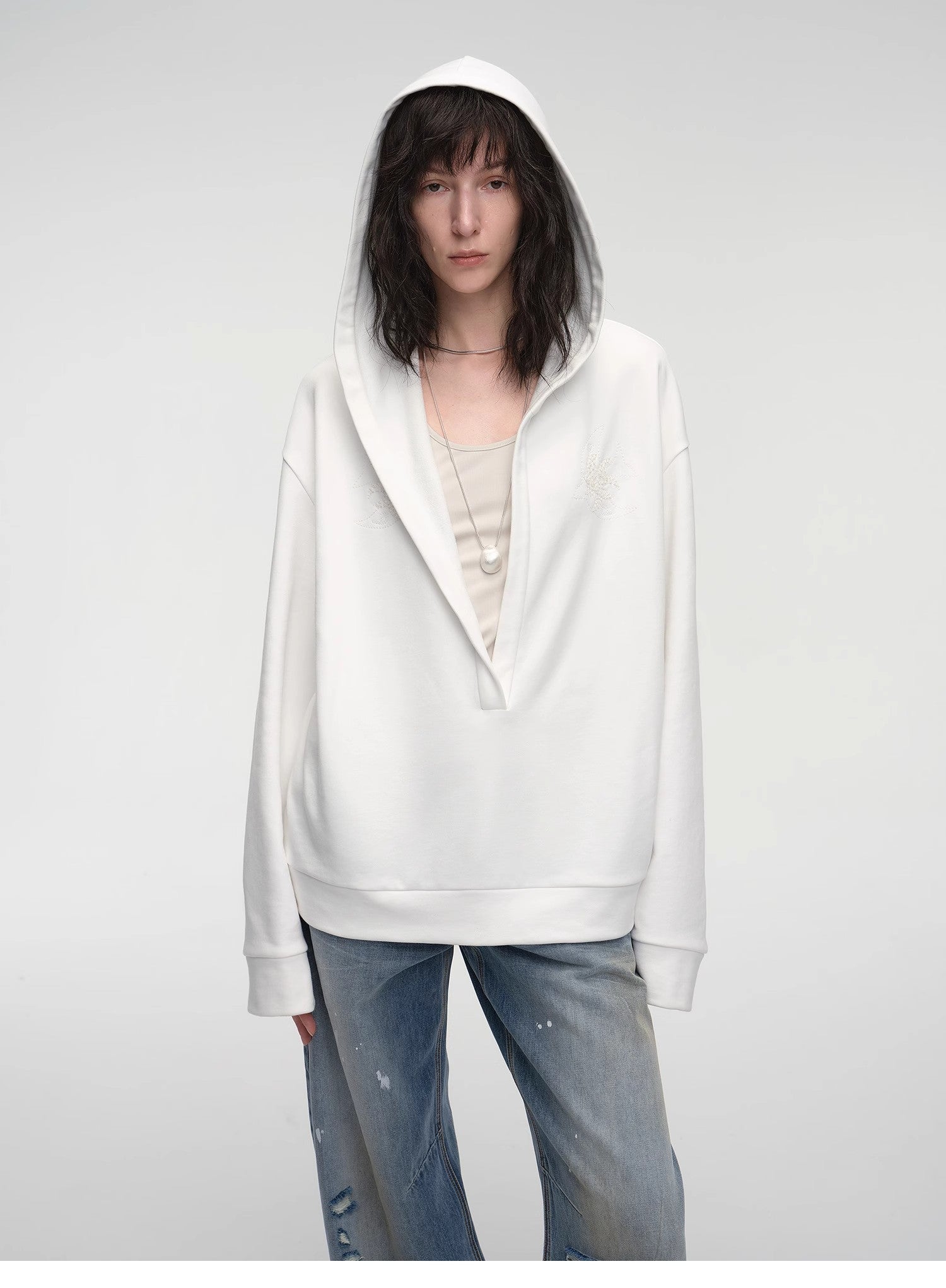 Person wearing a white hoodie and blue jeans on a plain background