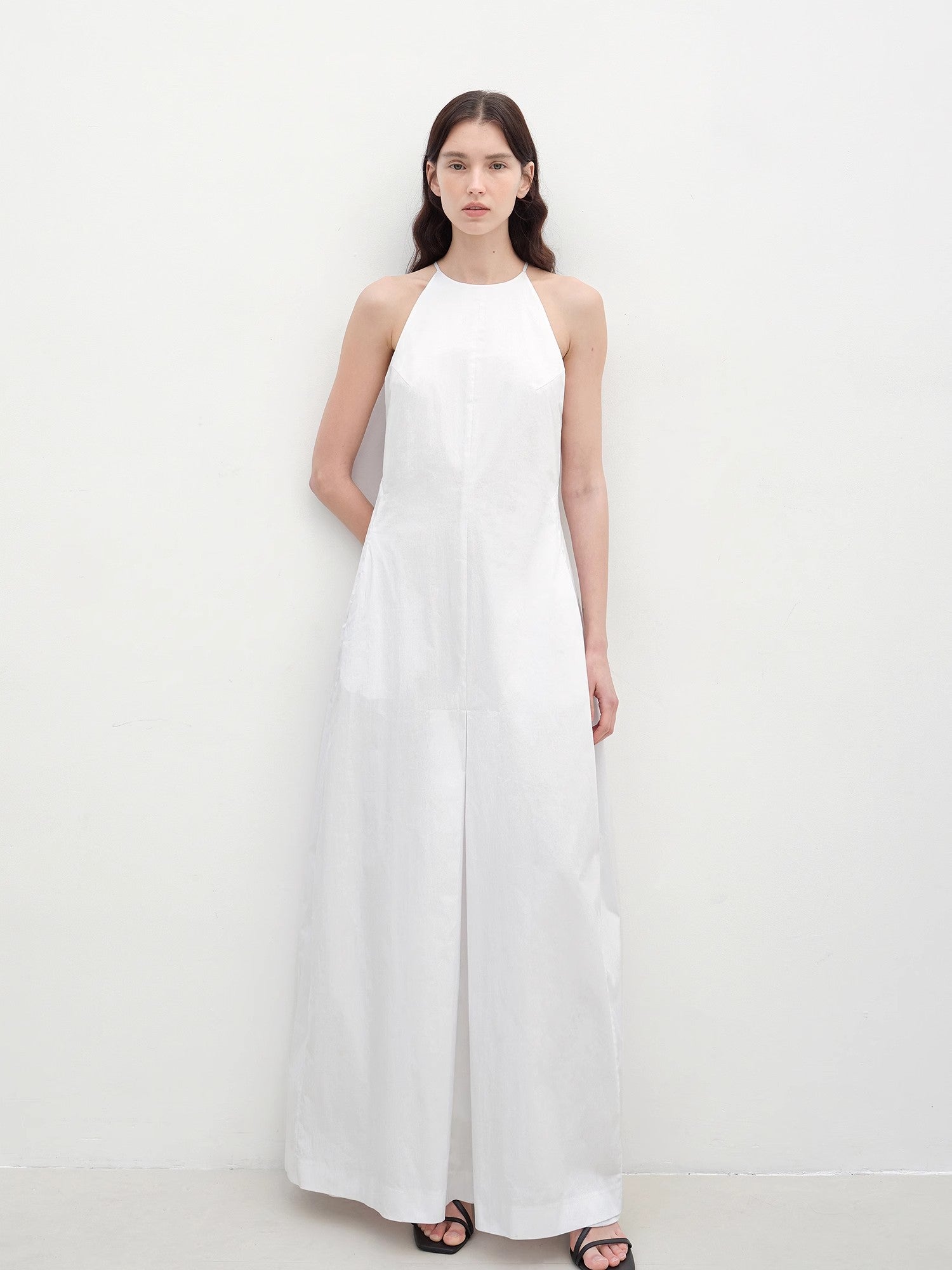 Woman wearing a white halter neck dress on a plain background