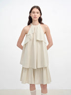 Woman wearing a beige halter neck dress on a white background