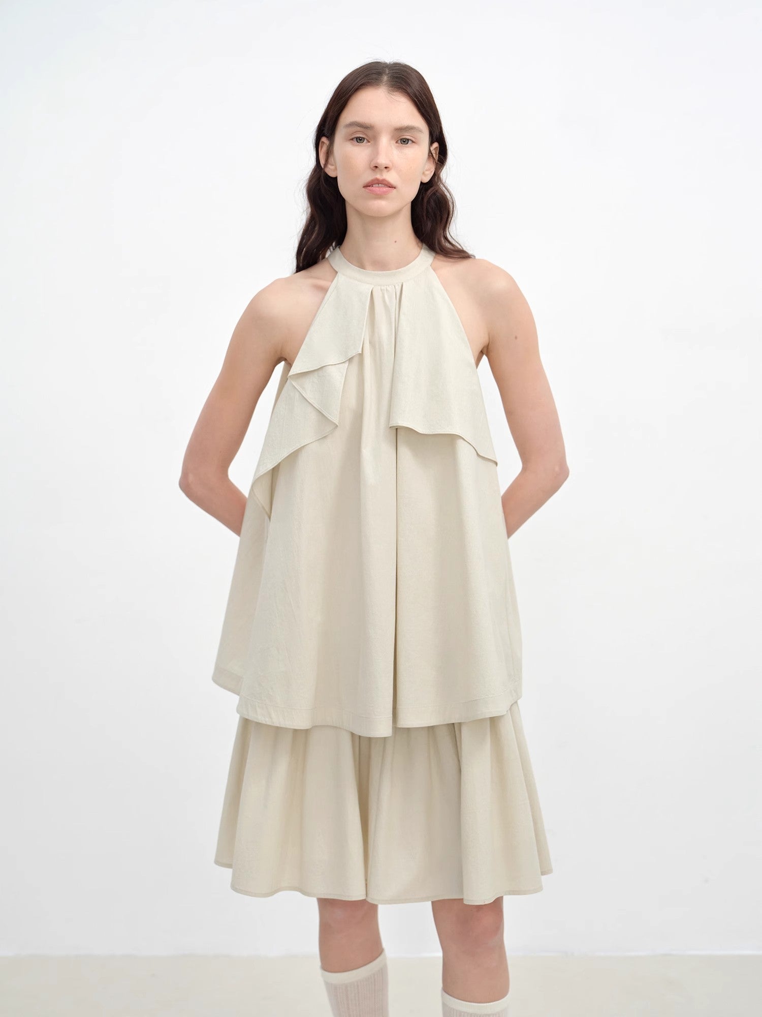 Woman wearing a beige halter neck dress on a white background