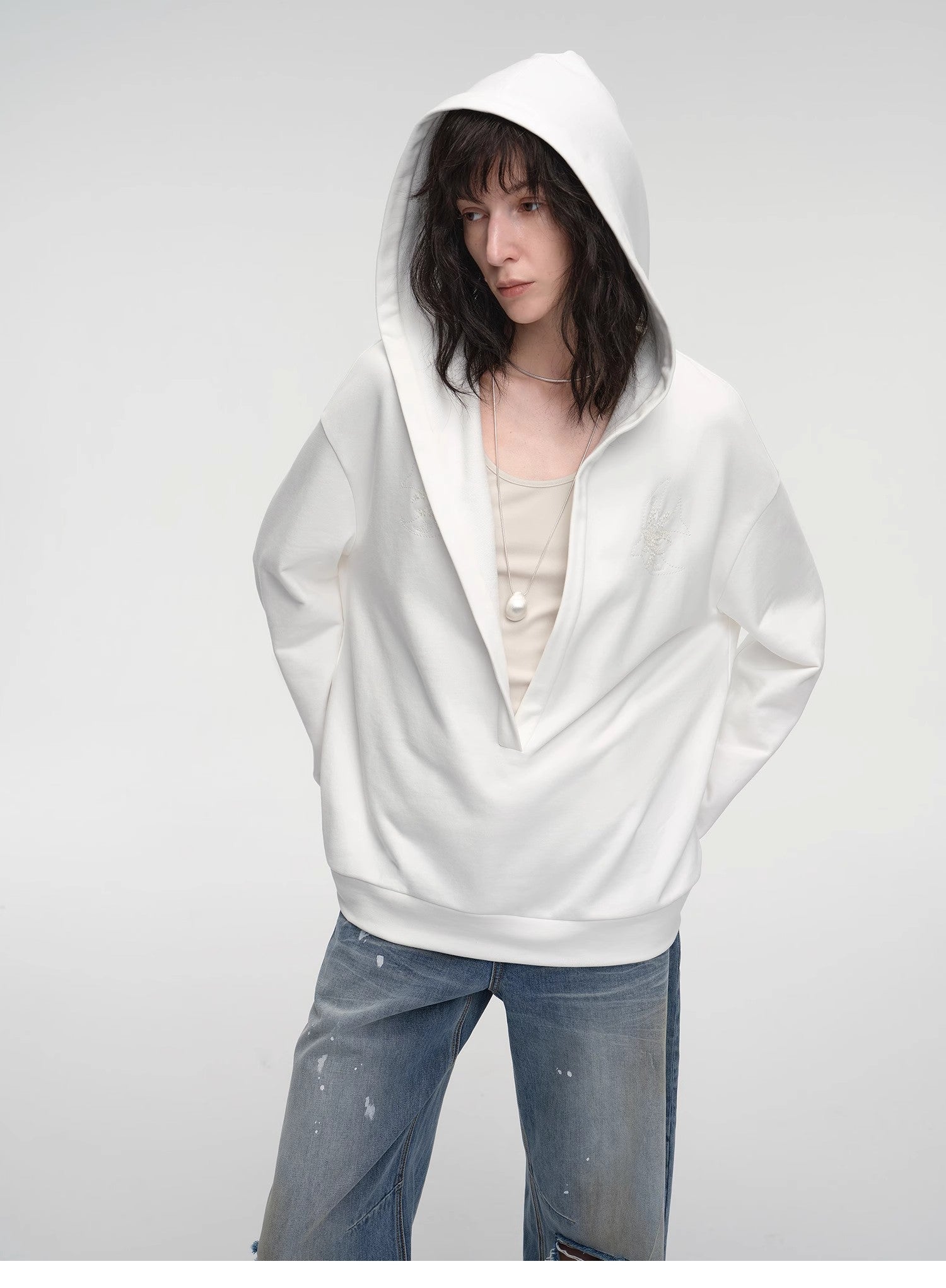 Person wearing a white hoodie and jeans on a plain background