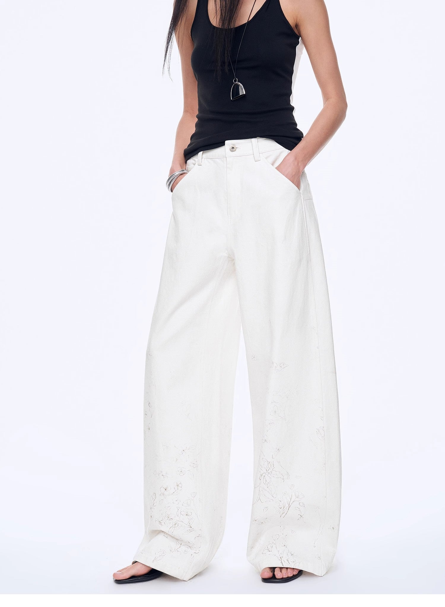 Person wearing a black sleeveless top and white wide-leg pants on a white background