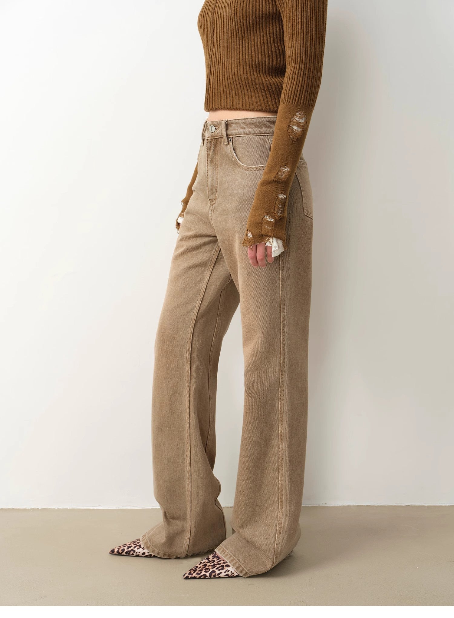 Person wearing beige pants and a brown top against a white background