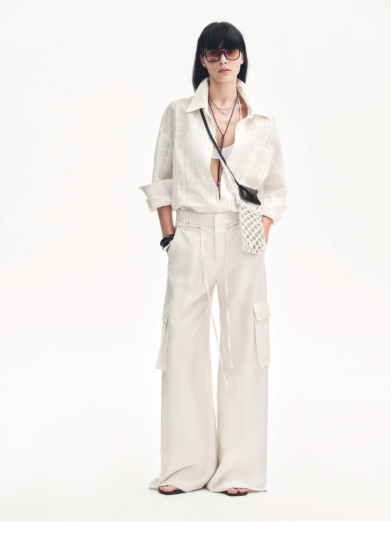 Woman wearing a white outfit with a black handbag on a white background