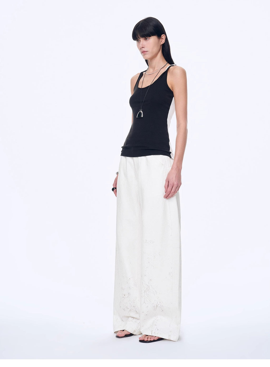 Woman wearing a black top and white pants on a white background