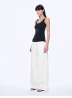 Woman wearing a black top and white pants on a white background