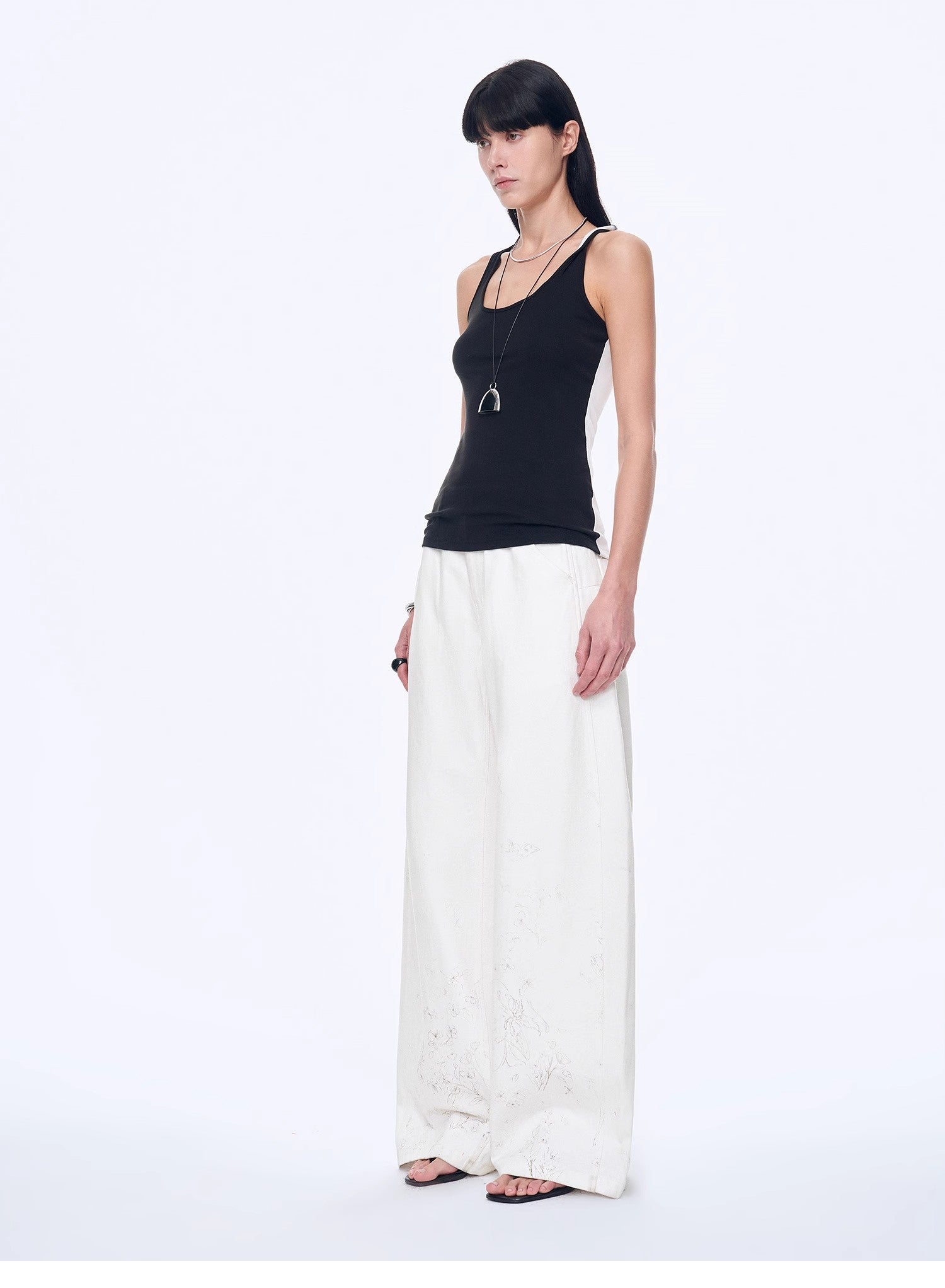 Woman wearing a black top and white pants on a white background