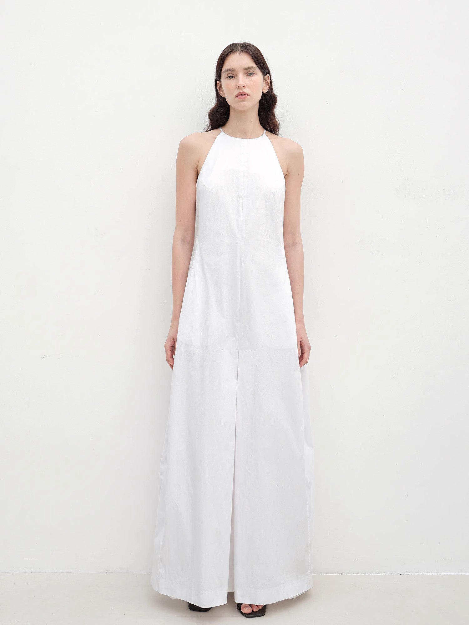Woman wearing a white halter neck dress on a plain background