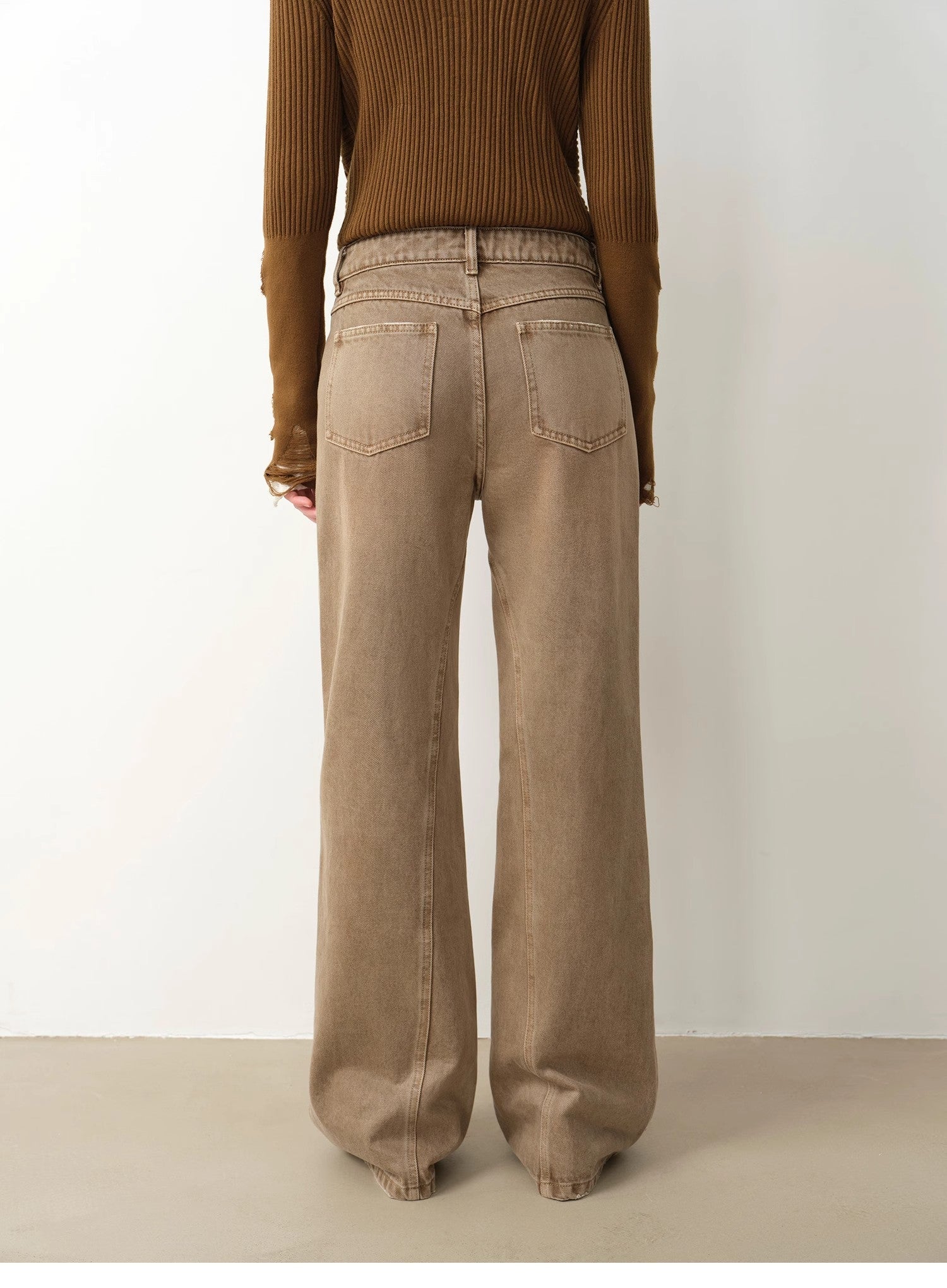 Person wearing a brown ribbed sweater and beige wide-leg pants on a white background