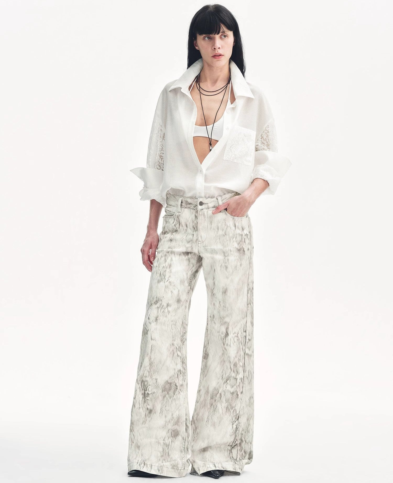 Woman wearing a white blouse and patterned pants on a white background