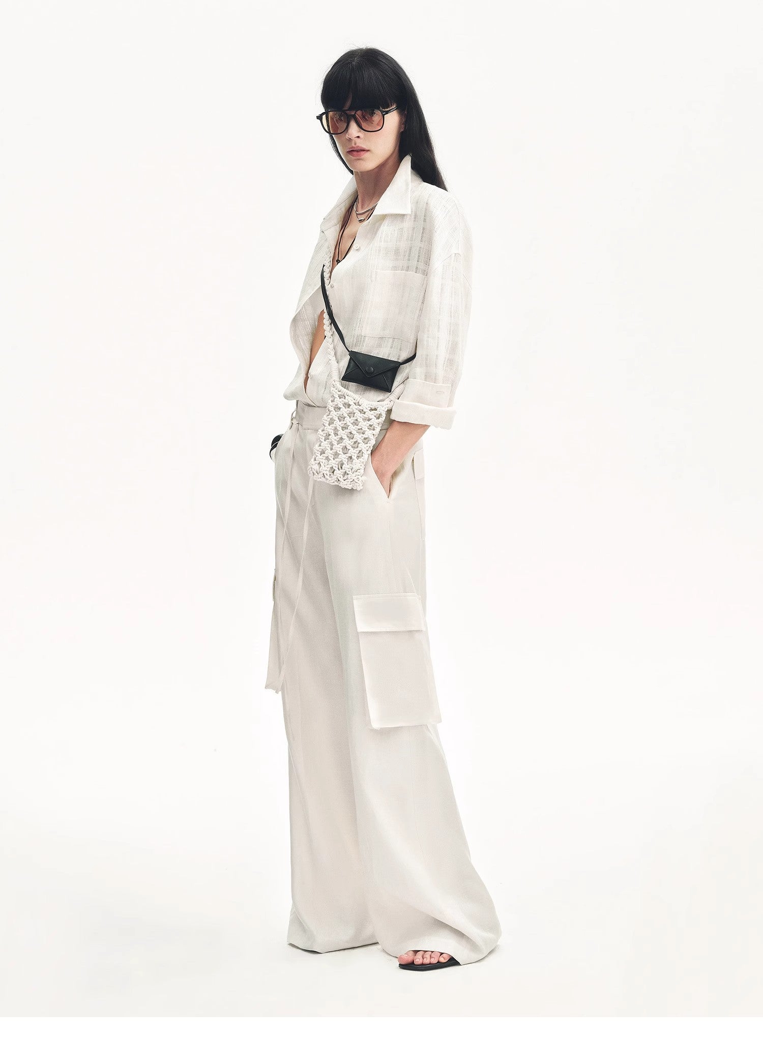 Woman in a white outfit with a black handbag on a white background