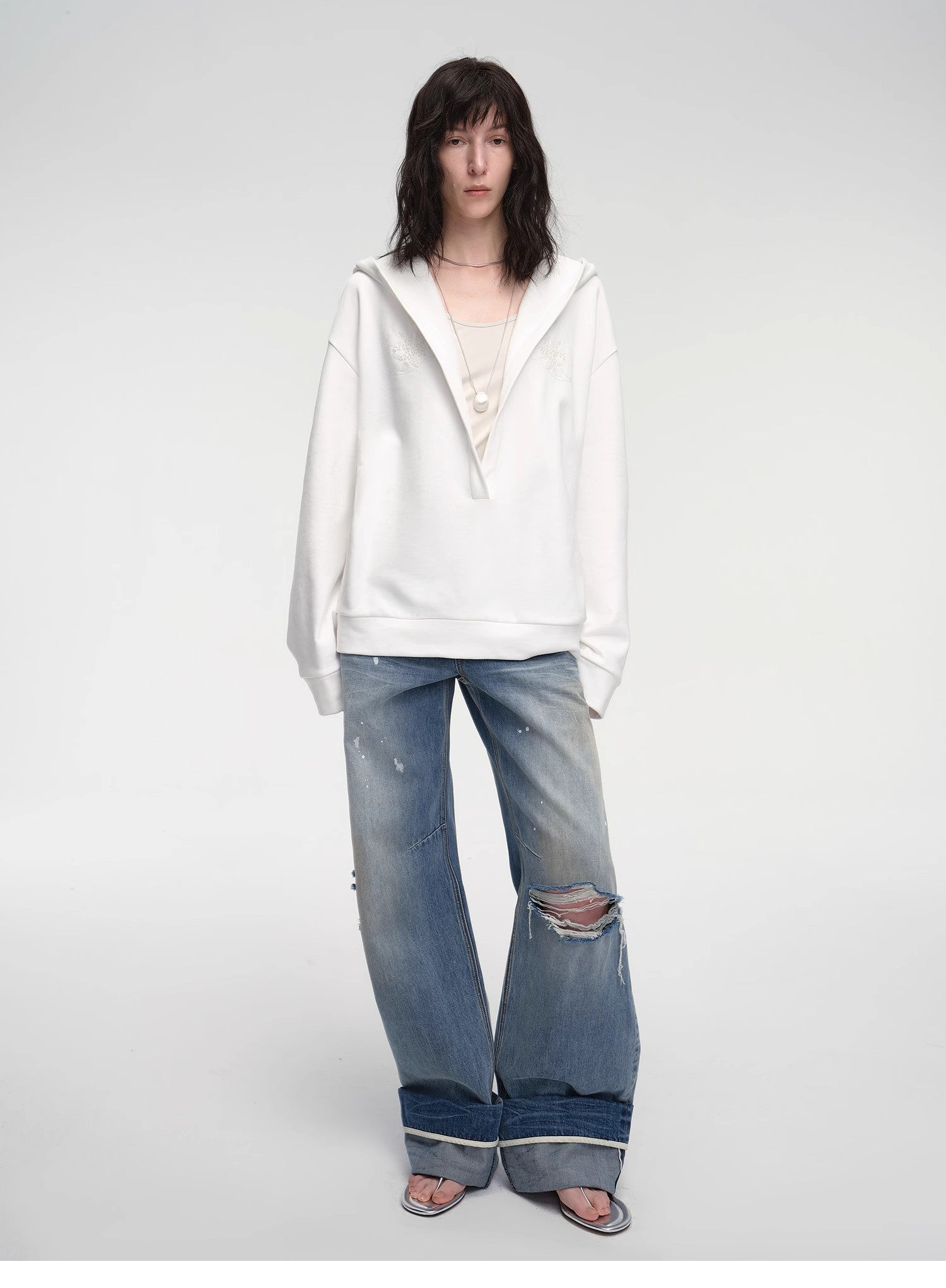 Person wearing a white hoodie and blue jeans on a plain background