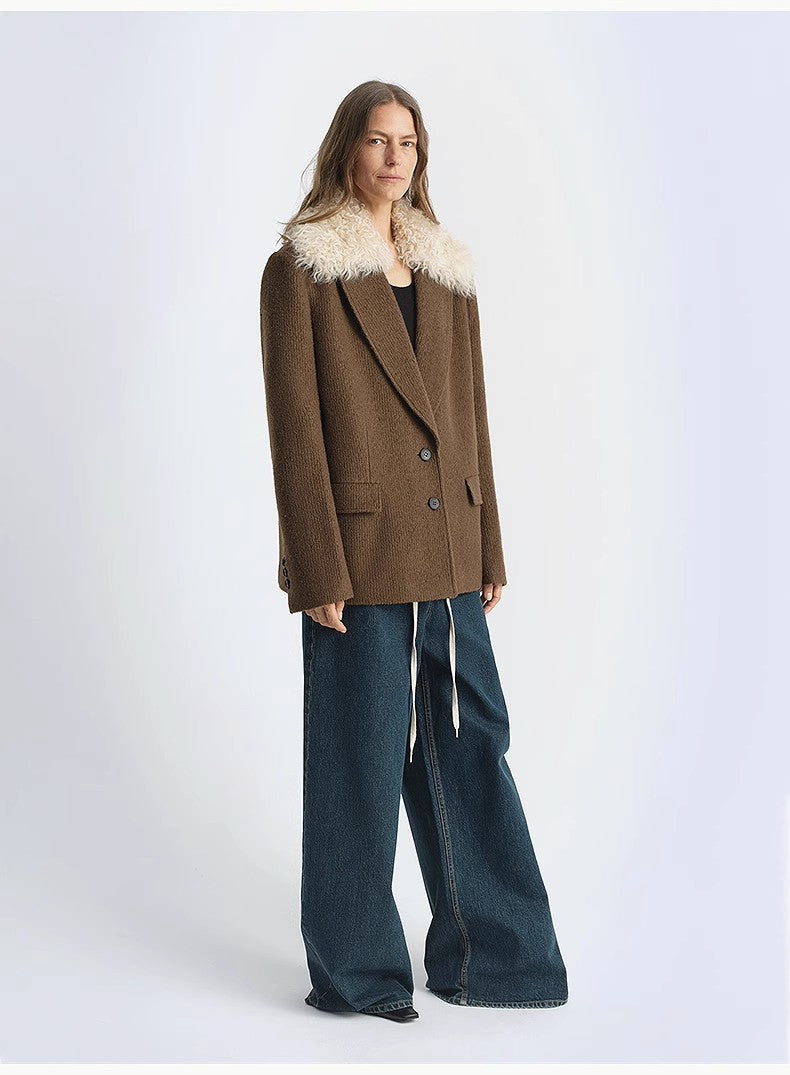 Person wearing a brown coat with fur collar and blue jeans on a white background