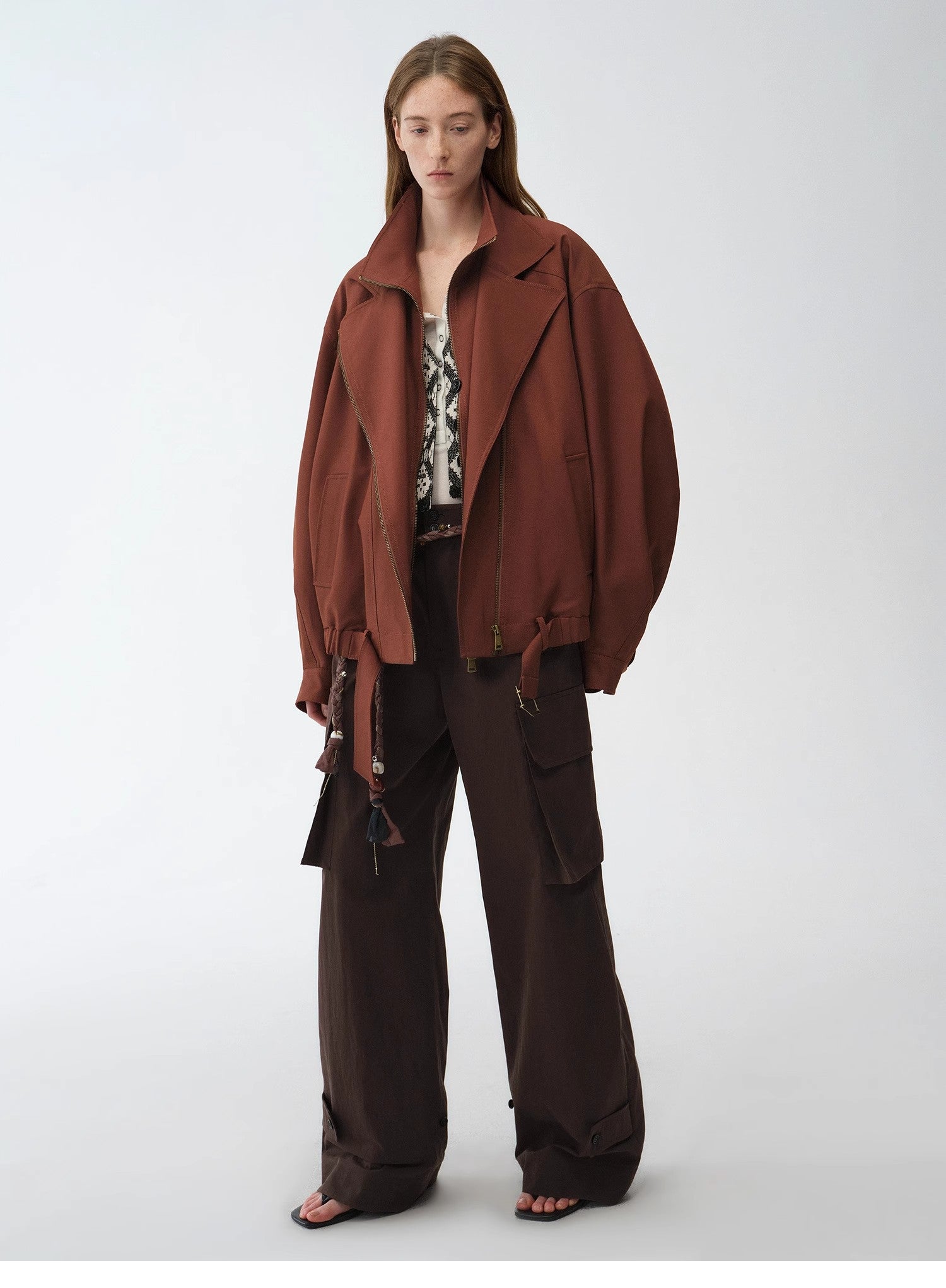 Person wearing a brown jacket and pants on a white background