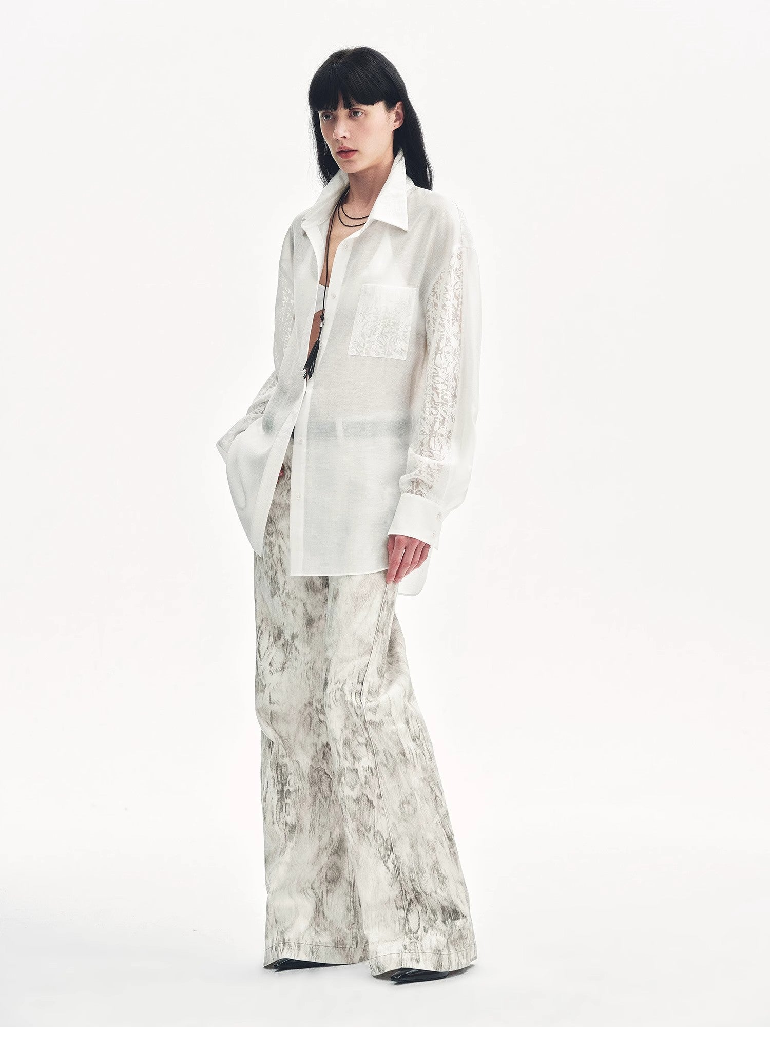 Woman wearing a white blouse and patterned pants on a white background