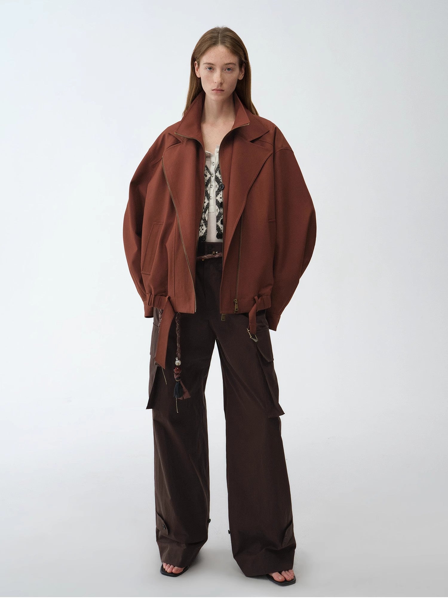 Model wearing a brown coat and pants on a white background